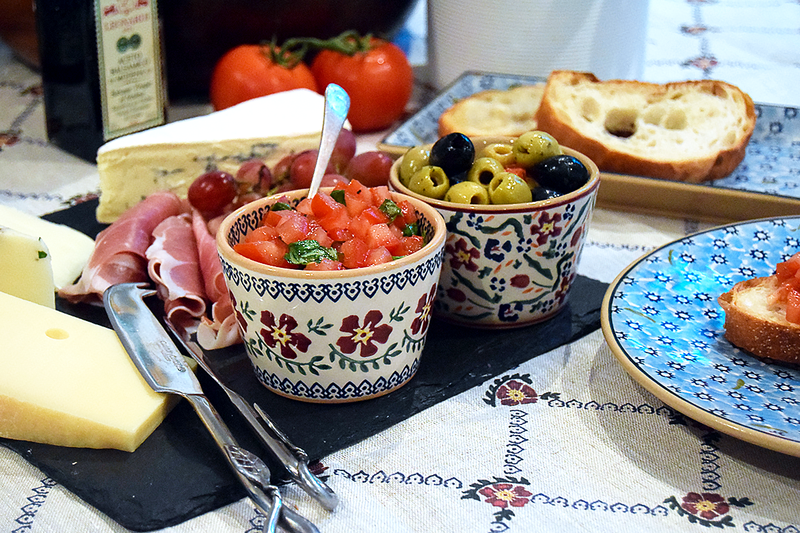 Nicholas Mosse Pottery Old Rose and Wild Flower Meadow Custard Cups filled with chopped tomatoes and olives. Placed on a cheese board.